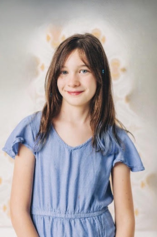 Mila smiling, in a blue dress